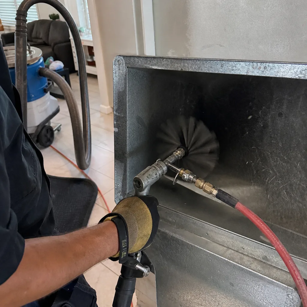 Professional technician performing air duct cleaning with rotating brush tool